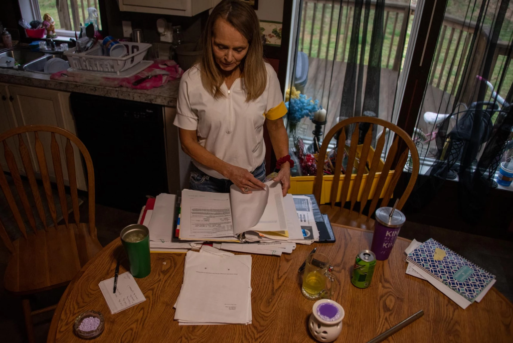 Photo by Justin Hicks Woman looks through mounds of paperwork